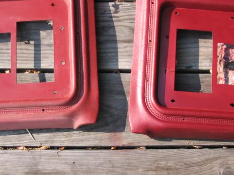 1985 Ford F-350 - Close-up of two red interior door panels resting on weathered wooden planks outdoors.
