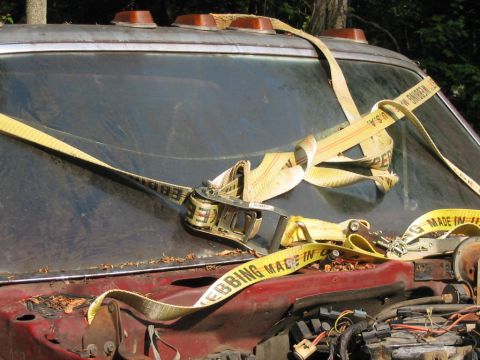 1985 Ford F-350 - Ratchet straps secure the hood of an old truck, with debris scattered across the surface.