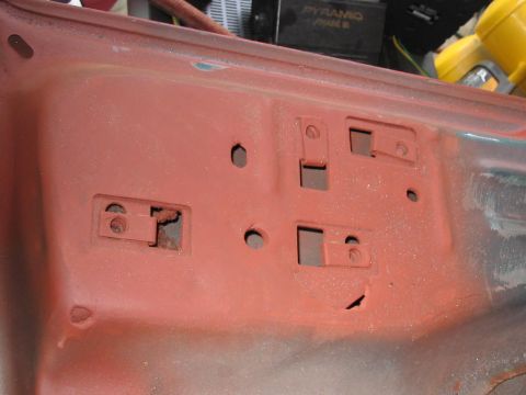 1985 Ford F-350 - The underside of a vehicle's hood shows the mounting points for the latch mechanism, with some surface rust visible.