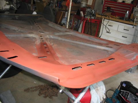1985 Ford F-350 - The underside of a car hood is shown, prepped with orange primer and revealing its internal bracing structure.