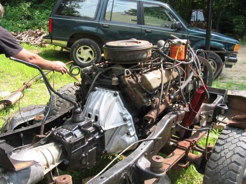 1985 Ford F-350 - A truck's engine and chassis are shown, with a green SUV parked behind it.