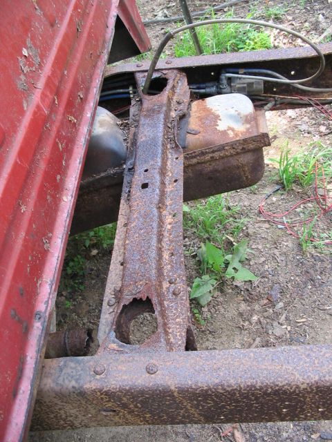 1985 Ford F-350 - The heavily rusted frame and fuel tank of an old truck are shown in this close-up view.