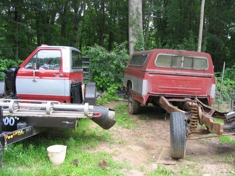 1985 Ford F-350 - Two pickup truck cabs are shown disassembled in a yard, one on a trailer and the other as a chassis with a bed and cap.