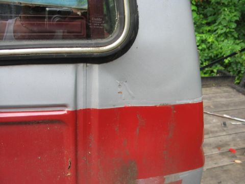 1985 Ford F-350 - Close-up of a two-tone truck cab shows signs of wear and tear, with visible rust on the lower red section.