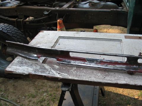 1985 Ford F-350 - A chrome trim piece is laid out on a workbench, with the frame of a truck visible behind it.