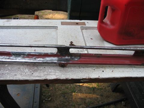 1985 Ford F-350 - Chrome trim piece with visible red paint, likely from a vehicle part.