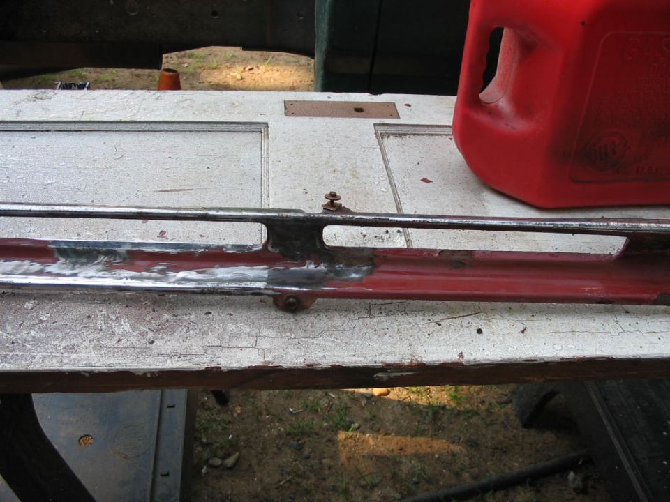 Chrome trim piece with red paint underneath, resting on a white surface