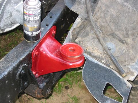 1985 Ford F-350 - A can of Dupli-Color Metalcast paint sits near a freshly painted red suspension part on a vehicle's frame.