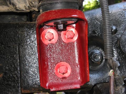 1985 Ford F-350 - Close-up of a red metal bracket with bolts, part of a vehicle's undercarriage.