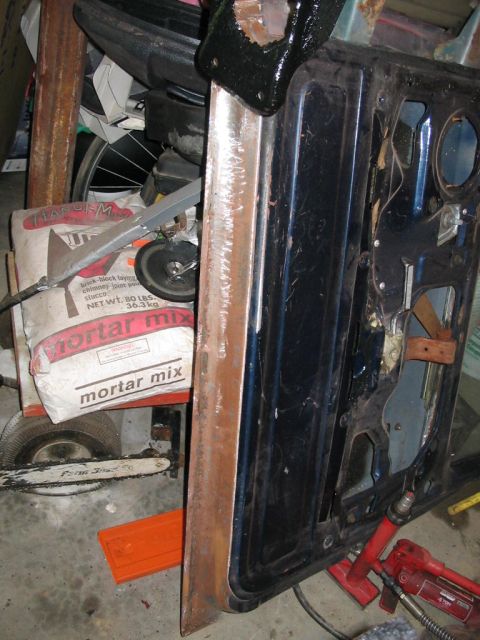1985 Ford F-350 - A disassembled vehicle door is shown leaning against construction materials in a cluttered space.