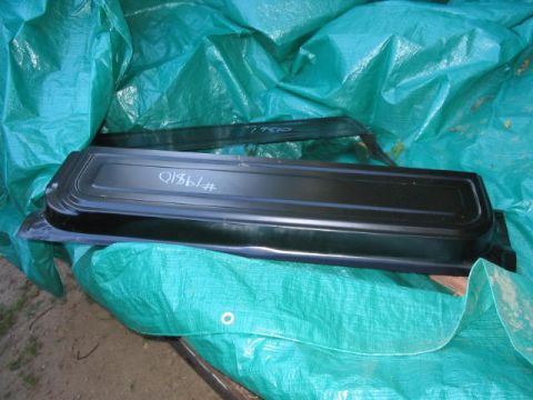 1985 Ford F-350 - A black tailgate panel, possibly for a truck, is covered by a green tarp. Blue writing is visible on the panel.