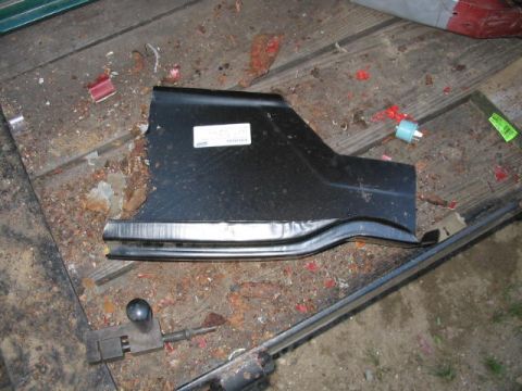 1985 Ford F-350 - A black metal car part rests on a weathered wooden surface scattered with debris.