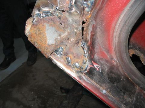 1985 Ford F-350 - Close-up of a heavily rusted and welded metal panel, showing extensive damage and repair work.
