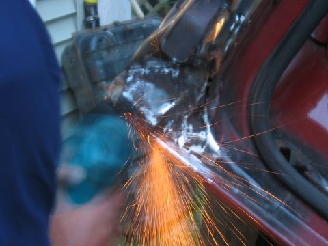 1985 Ford F-350 - Sparks fly as metal is ground away on a red vehicle's bodywork during a repair or modification.