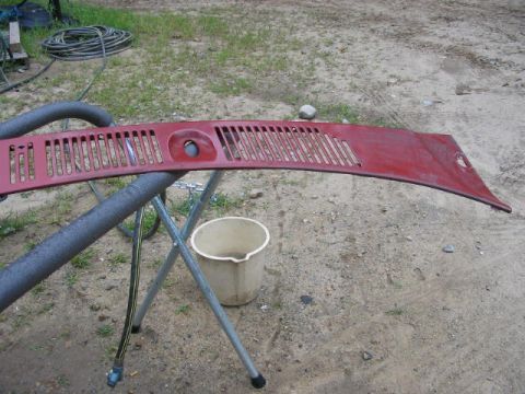 1985 Ford F-350 - Windshield cowl vent panel, likely from a truck, is red and mounted on a stand outdoors.