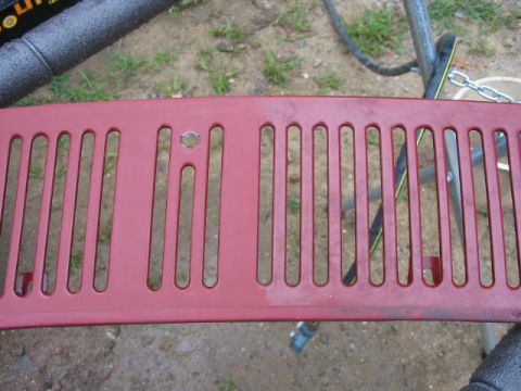 1985 Ford F-350 - A red truck grille is shown up close, with a portion of a black blower in the background.