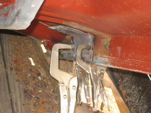 1985 Ford F-350 - Welding clamps are used to hold a metal bracket in place on a red painted frame.