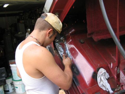 1985 Ford F-350 - A person is welding a section of the red interior of a vehicle, with sparks visible.