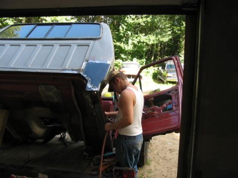 1985 Ford F-350 - A person works on the bed of a red truck, with another vehicle visible in the background.