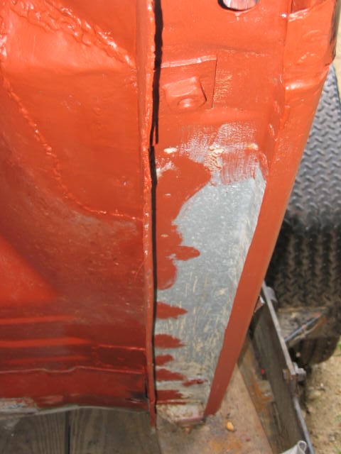 1985 Ford F-350 - The image shows a close-up view of a vehicle's frame, with visible orange paint and a tire in the background.