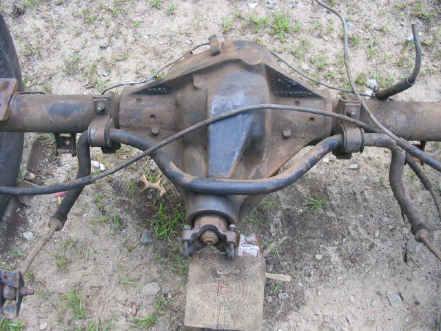 Rear axle assembly with brake lines and driveshaft connection, resting on wood blocks