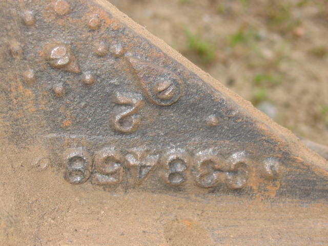 Close-up of a rusty metal part with stamped numbers 857880