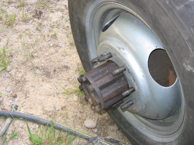 Close-up of a truck's wheel hub with lug nuts and a portion of the tire. A Supermotors.net watermark is visible