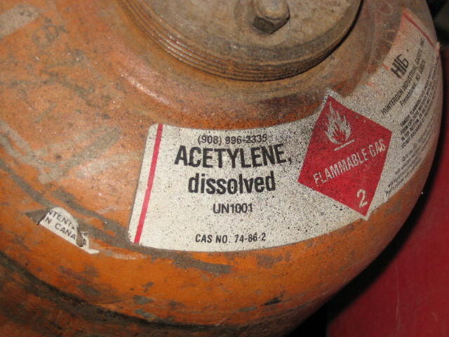 Orange acetylene gas cylinder with flammable gas label