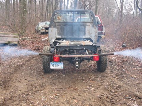 1985 Ford F-350 - This heavily modified truck, possibly a 1985 Ford F-350, is seen from the rear with smoke billowing from its custom exhaust pipes.