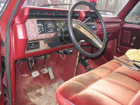 1985 Ford F-350 - The interior of this truck features a wood-grain dash panel and red upholstery, with tools visible on the passenger seat.