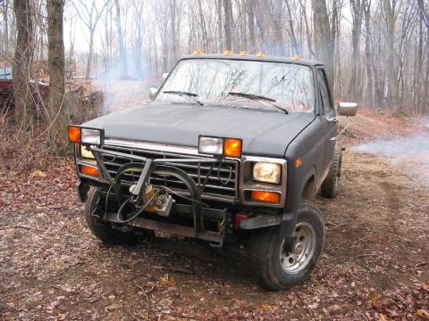 1985 Ford F-350 - This black pickup truck, likely from the early 1980s, is seen in a wooded area with smoke coming from its exhaust.