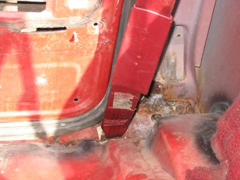 1985 Ford F-350 - Close-up of the interior door jamb and seatbelt anchor area of a 1985 Ford F-350, showing signs of rust.