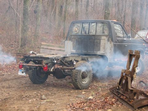 1985 Ford F-350 - This 1985 Ford F-350 pickup truck is seen from the rear, its frame exposed and exhaust emitting smoke in a wooded area.