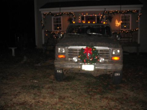 1985 Ford F-350 - A muddy Ford F-Series truck is parked in front of a house adorned with festive Christmas lights.