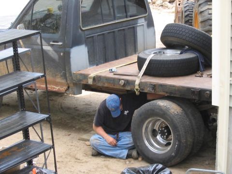 1985 Ford F-350 - Man works on the rear axle of a 1985 Ford F-350 flatbed truck.