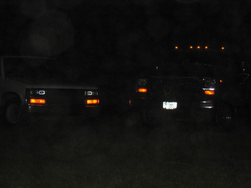 Two pickups at night showing amber parking lights and cab-roof clearance lights