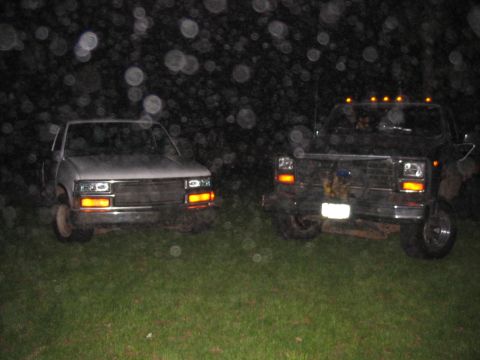 1985 Ford F-350 - Two pickup trucks are parked on a grassy area at night, with lights on.