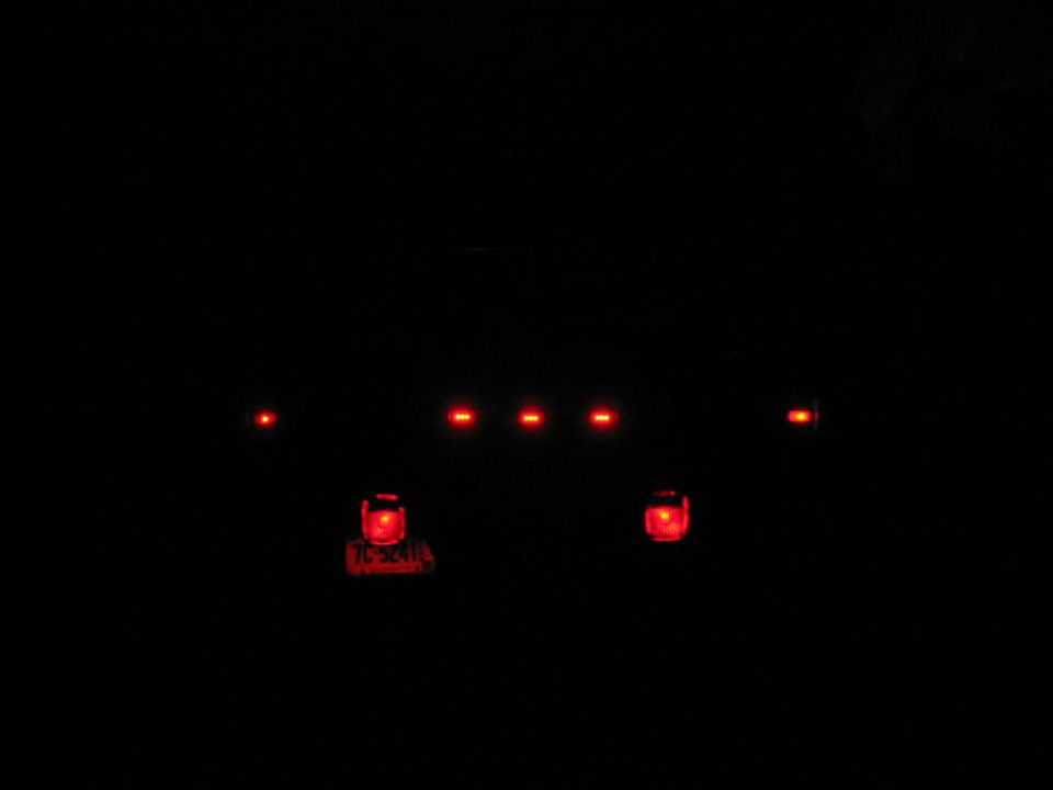 Red taillights and marker lights of a vehicle glowing in the dark at night