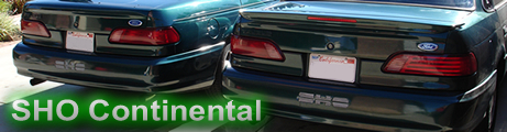 1993 Ford Taurus - Rear view of two dark green 1993 Ford Taurus sedans, one partially obscured by the other.