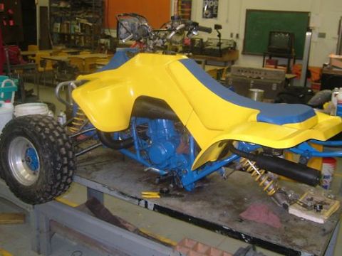 1992 Ford Crown Victoria - An ATV with yellow body panels and a blue seat sits on a workbench in a garage.