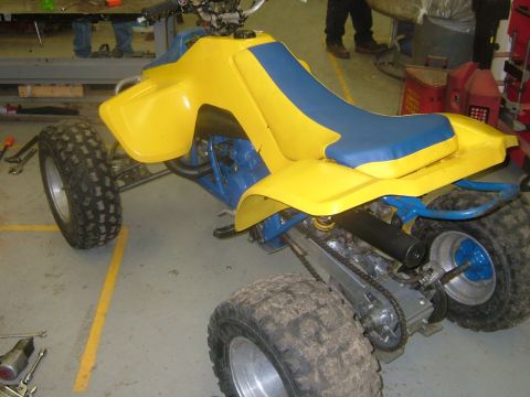 1992 Ford Crown Victoria - An ATV with yellow body panels and a blue seat sits in a workshop environment.