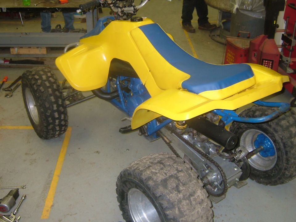 Yellow and blue ATV with knobby tires and a blue frame, seen from the right front