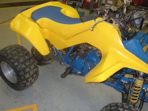 1992 Ford Crown Victoria - This yellow and blue ATV features a two-tone seat and knobby tires, seen from the side.