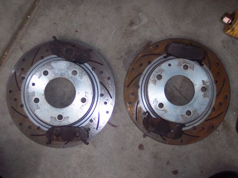 1995 Ford Probe - Close-up view of two worn brake rotors and their associated brake pads.