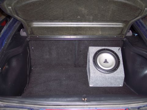 1995 Ford Probe - The trunk of a car features a JL Audio subwoofer installed in a grey enclosure.