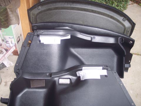 1995 Ford Probe - Close-up of a black plastic car trunk interior panel, showing mounting points and textured surfaces.