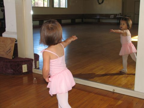 1984 Ford Bronco - A young dancer practices her moves in front of a large mirror in a wooden-floored studio.