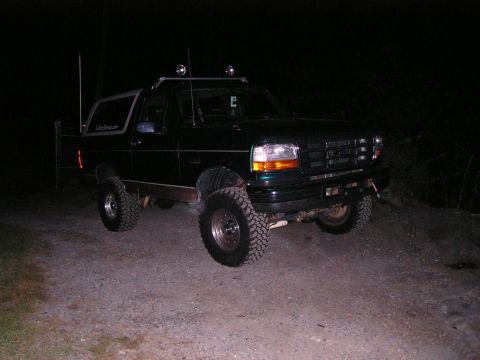 1996 Ford Bronco - This lifted 1996 Ford Bronco is parked on a dirt surface at night.