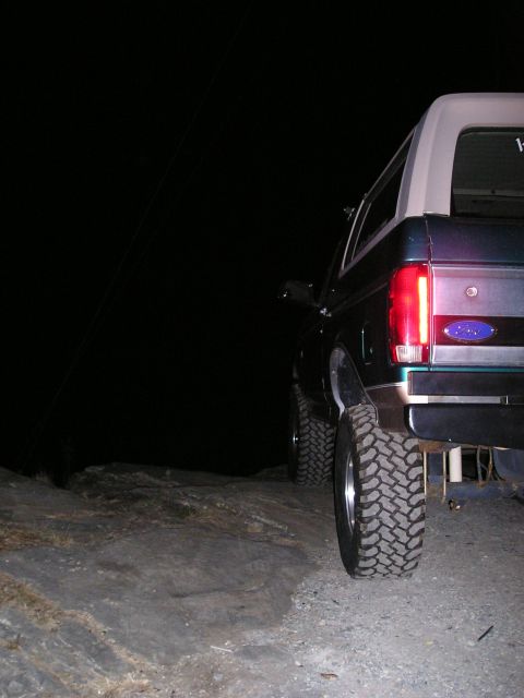 1996 Ford Bronco - A lifted 1996 Ford Bronco is parked on rocky terrain at night, with its rear visible.