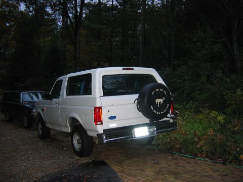1995 Ford Bronco - Rear view of a white 1995 Ford Bronco XL with a spare tire cover, parked outdoors.